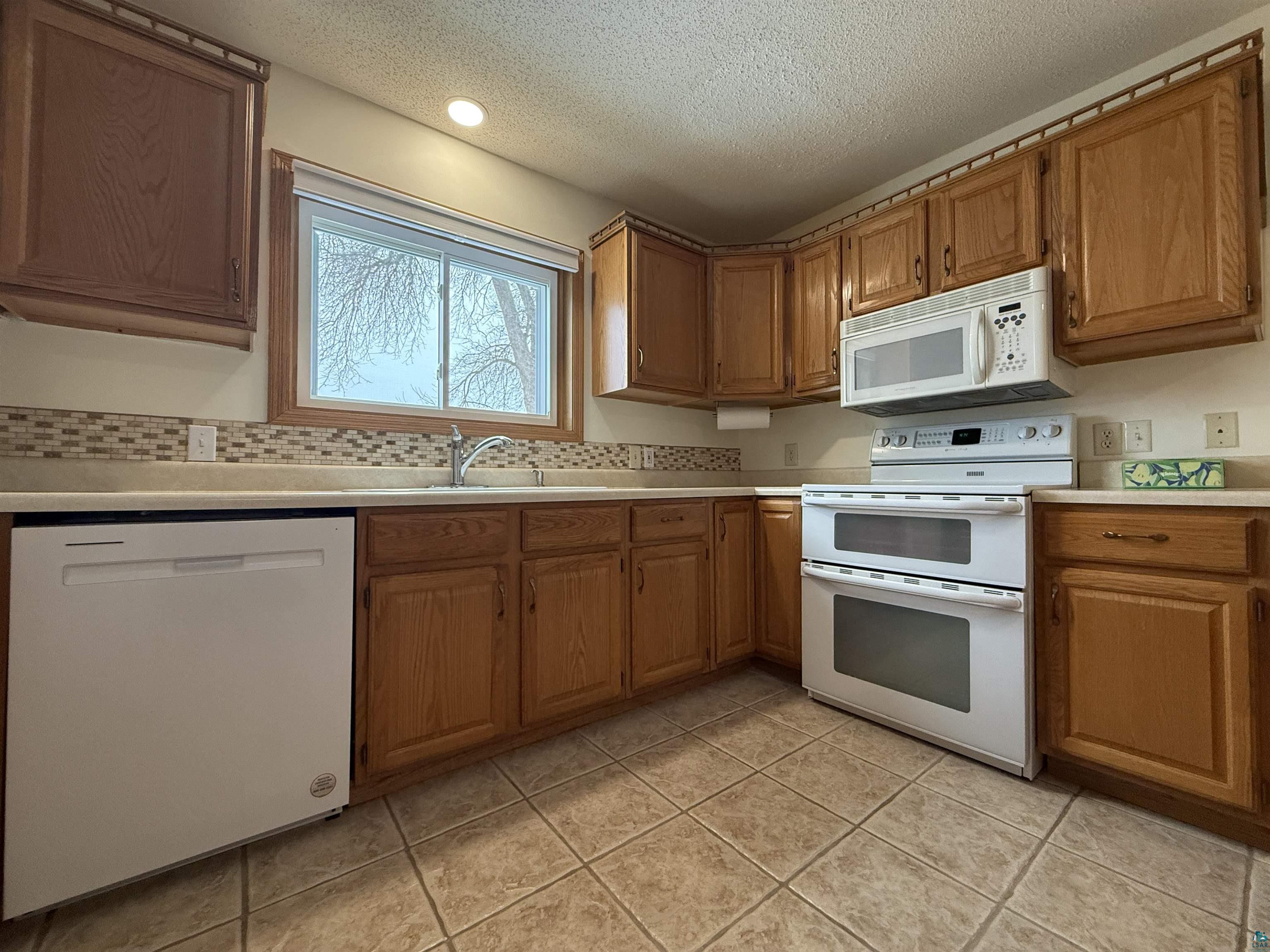 1321 South 13th Street Virginia, MN 55792 - Photo 7 of 33 Kitchen featuring white appliances, light countertops, wood finish cabinetry, and a textured ceiling