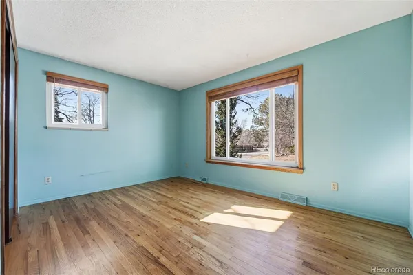 an empty room with wooden floor and window