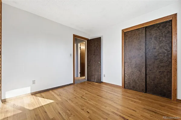 a view of an empty room with wooden floor and closet