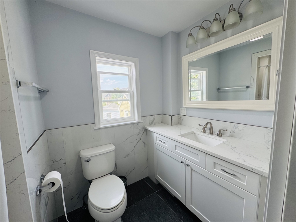 48 South Bow Street, Unit 1 Milford, MA 01757 - Photo 3 of 5 a bathroom with a toilet sink vanity granite and mirror
