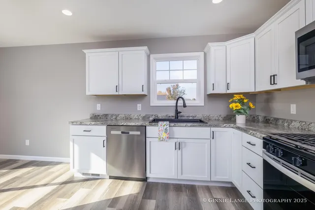 a kitchen with granite countertop a stove sink and cabinets