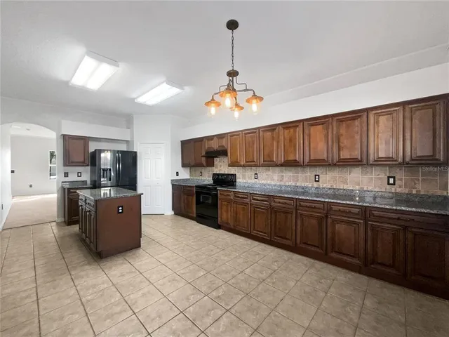 a large kitchen with kitchen island granite countertop a stove top oven a sink dishwasher and a refrigerator