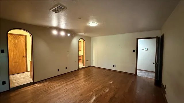 an empty room with wooden floor fan and windows