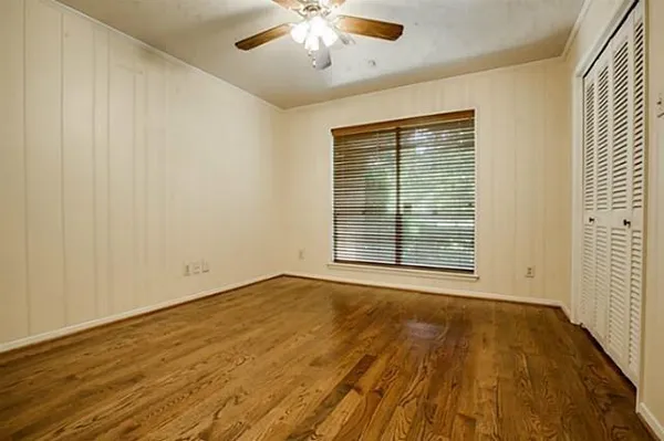 an empty room with wooden floor fan and windows