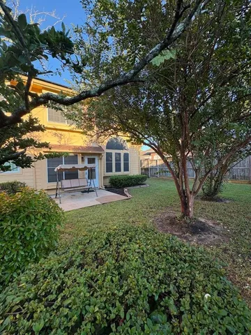 a view of house with outdoor seating and covered with trees