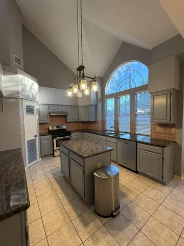 a kitchen with stainless steel appliances granite countertop a sink a stove and a refrigerator