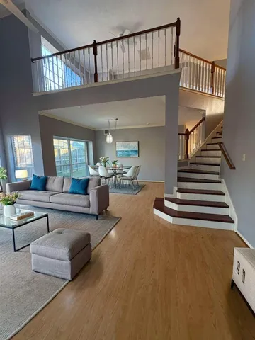 a living room with furniture wooden floor and a dining table