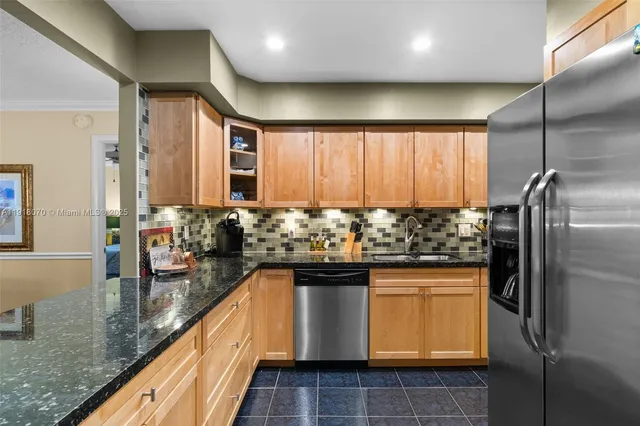 a kitchen with stainless steel appliances granite countertop a refrigerator a stove and a sink