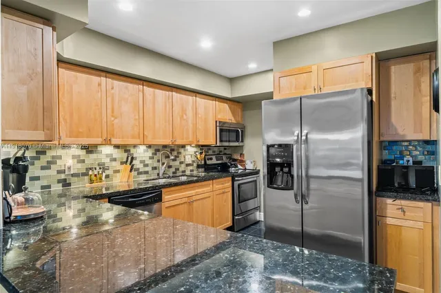 a kitchen with stainless steel appliances granite countertop a sink and a refrigerator