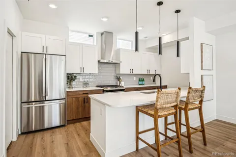 a kitchen with stainless steel appliances granite countertop a refrigerator a sink dishwasher a stove and white cabinets with wooden floor