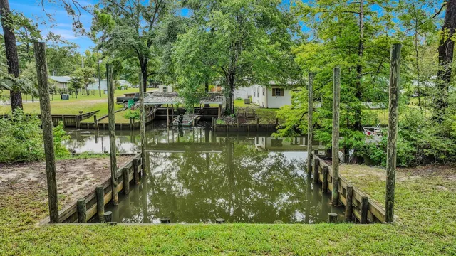a view of small pool with lawn chairs and a dining table and chairs with wooden fence