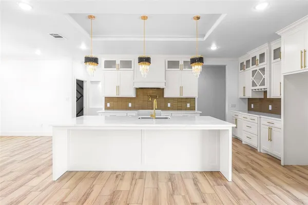 a view of kitchen with stainless steel appliances granite countertop a sink dishwasher a refrigerator and white cabinets with wooden floor