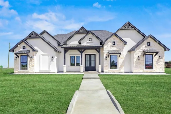 a front view of a house with a yard and large trees