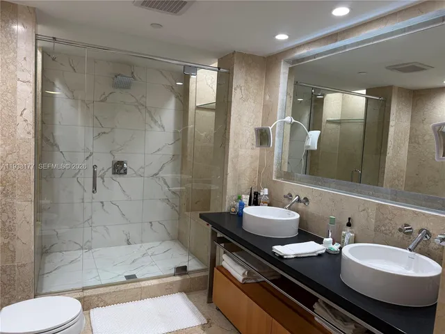 a bathroom with a double vanity sink toilet mirror and shower