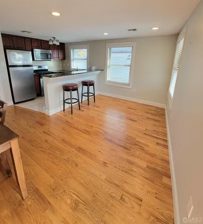 a room with stainless steel appliances wooden floors wooden cabinets a dining table and chairs