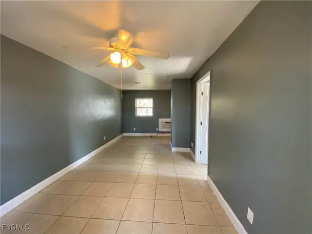 a view of an empty room and window and chandelier fan