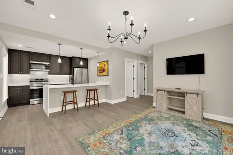 a kitchen with stainless steel appliances kitchen island granite countertop a refrigerator a stove a sink dishwasher and white cabinets with wooden floor