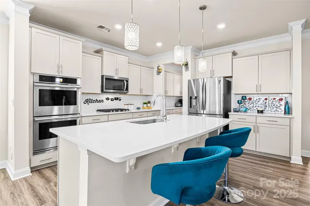 a kitchen with a refrigerator a stove a sink and white cabinets with wooden floor