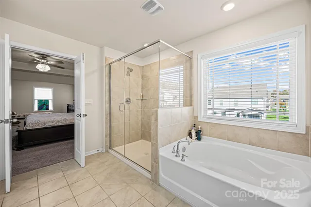 a spacious bathroom with a tub shower and windows