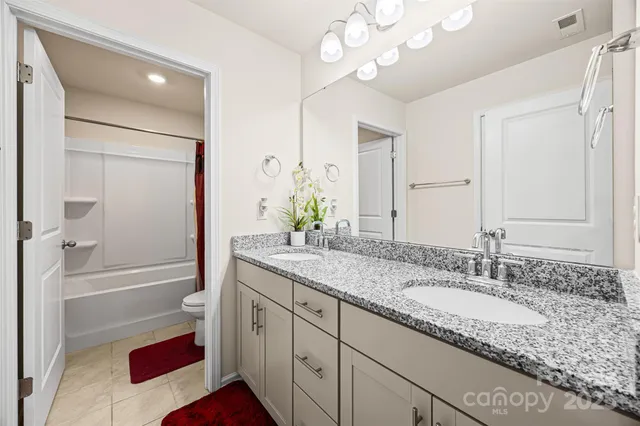 a bathroom with a granite countertop sink a mirror and a bathtub