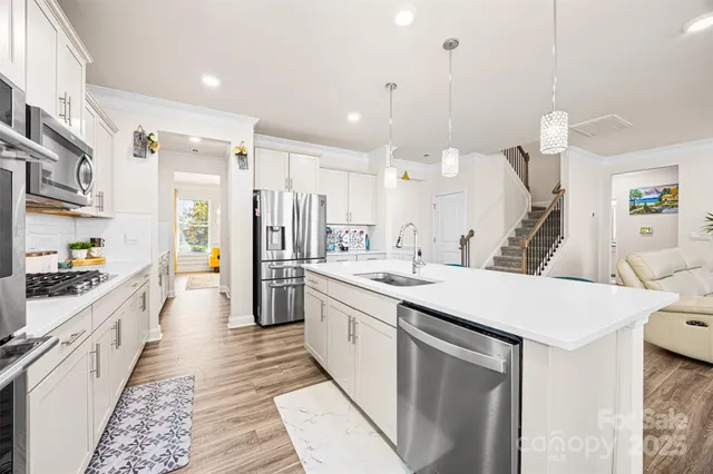 a large kitchen with stainless steel appliances kitchen island a large counter top a sink a stove and a refrigerator