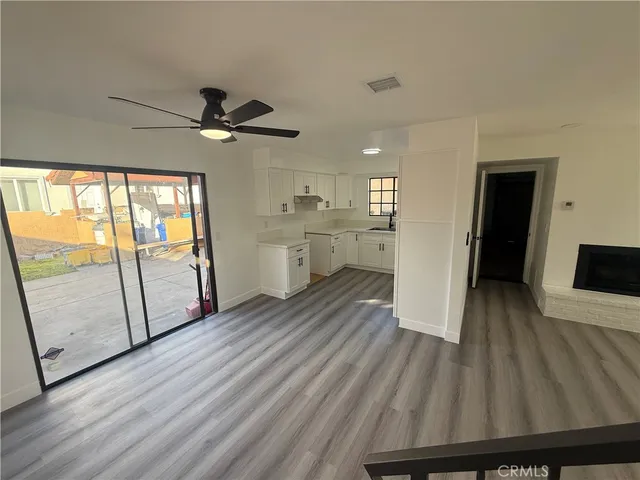 a view of hallway with wooden floor and fan
