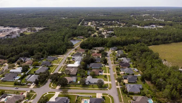 an aerial view of residential houses with outdoor space and parking