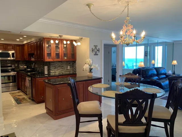 a view of a dining room with furniture a chandelier and kitchen view
