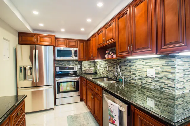 a kitchen with stainless steel appliances granite countertop a refrigerator a stove a sink and dishwasher