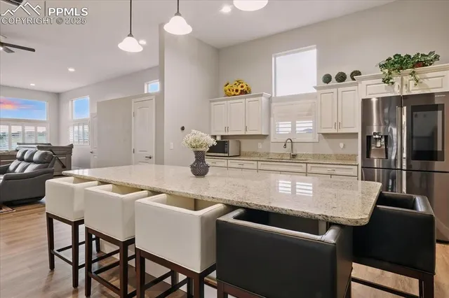 a kitchen with stainless steel appliances granite countertop a dining table chairs and a refrigerator