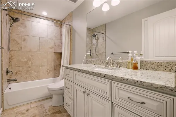 a bathroom with a granite countertop sink a toilet and bathtub