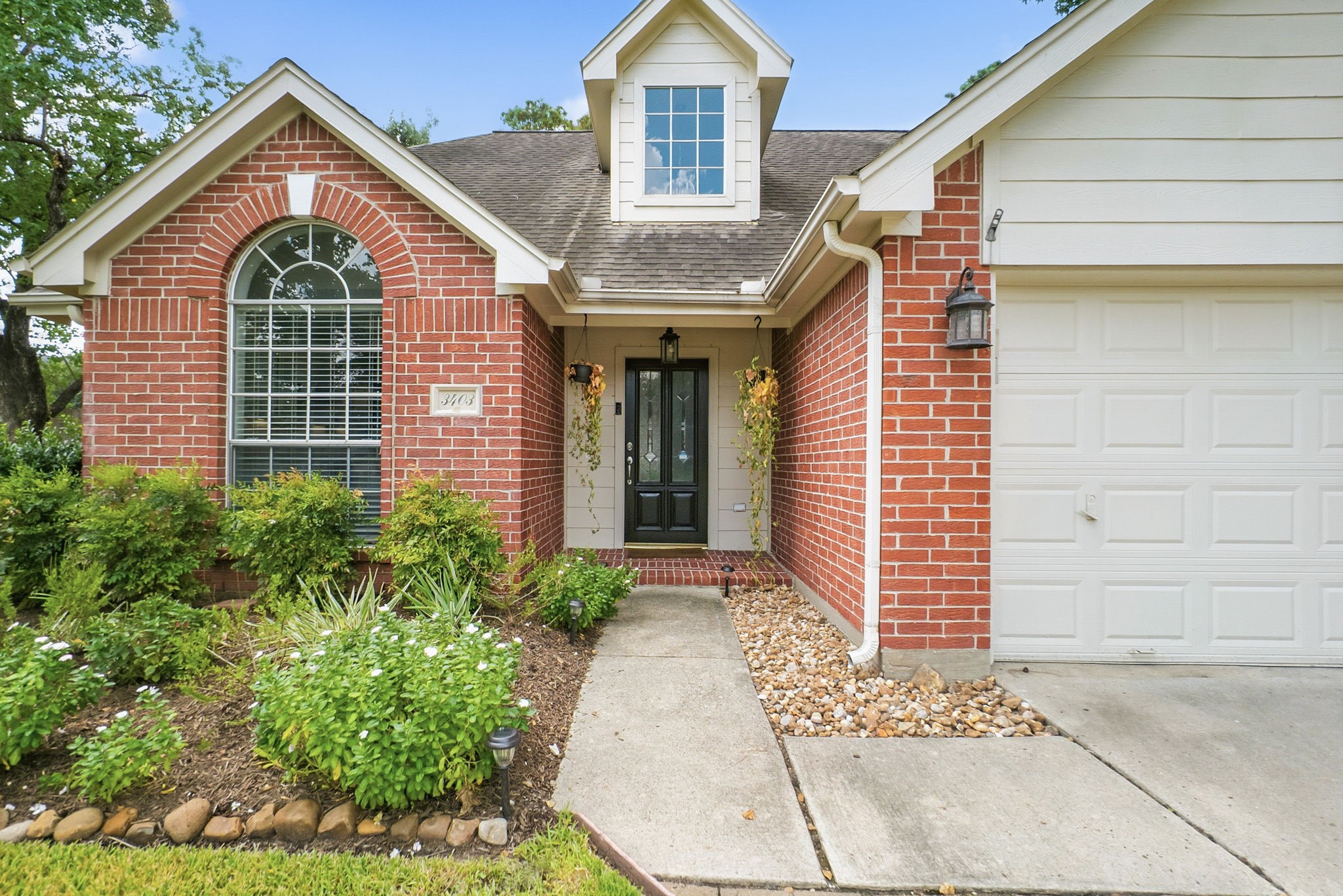 3403 Arromanches Lane Spring, TX 77388 - Photo 4 of 39 Landscaped beds add beauty and color. The stained wood front door with glass, arched window, and dormer window add architectural interest and character.