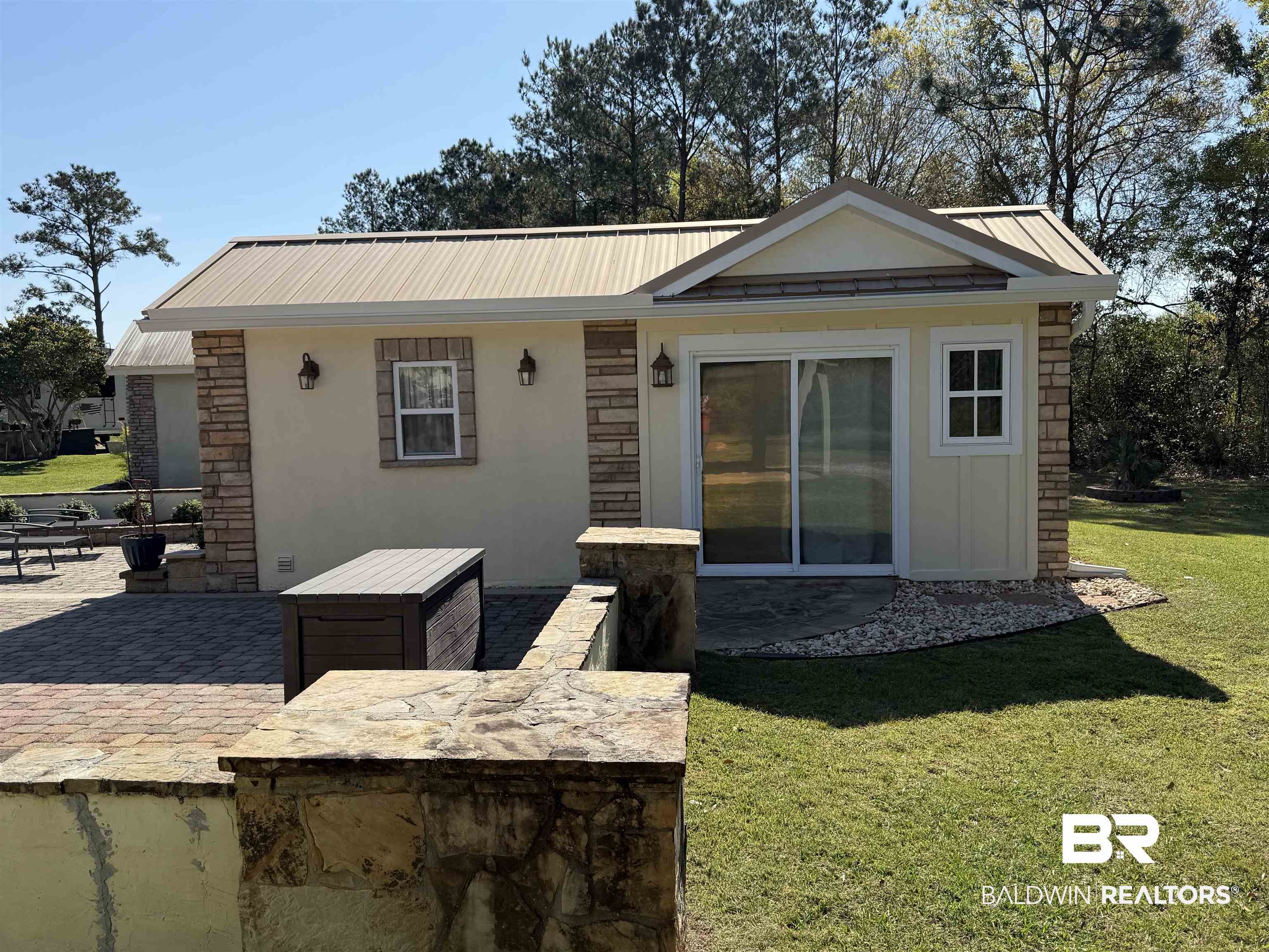 28114 Preserve Trail, Unit 190 Elberta, AL 36530 - Photo 17 of 69 Rear view of house featuring a yard, stone siding, a patio area, stucco siding, and a metal roof