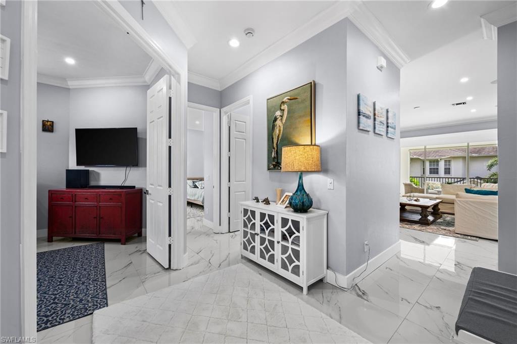 5010 Marina Cove Drive, Unit 4 Naples, FL 34112 - Photo 22 of 42 a spacious bedroom with a bed a mirror on dresser and a flat screen tv