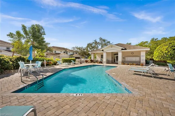 a view of a white house next to a yard with potted plants and palm trees