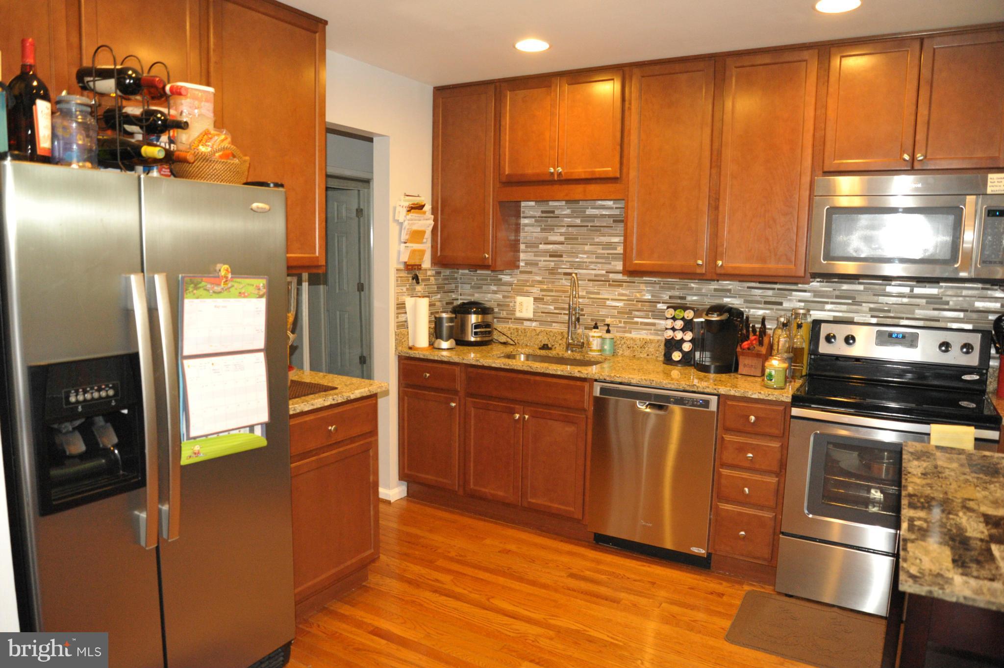 8591 Tyrolean Way Springfield, VA 22153 - Photo 8 of 29 a kitchen with stainless steel appliances granite countertop a refrigerator a sink dishwasher a stove with wooden cabinets and floor