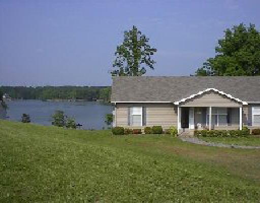a front view of a house with a garden and lake view