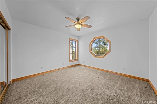 an empty room with windows and a chandelier fan