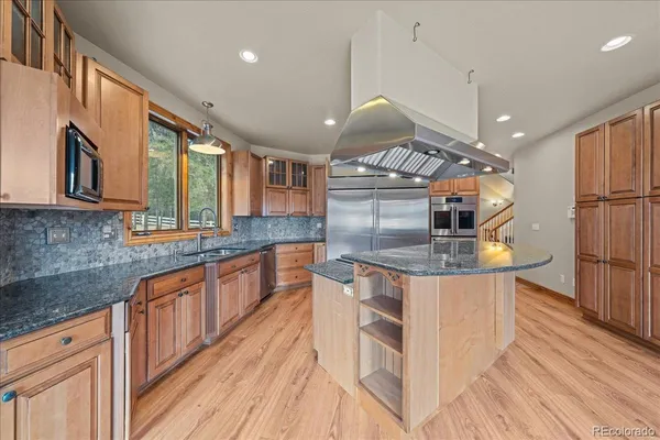a kitchen with stainless steel appliances granite countertop a sink a stove and a wooden floors
