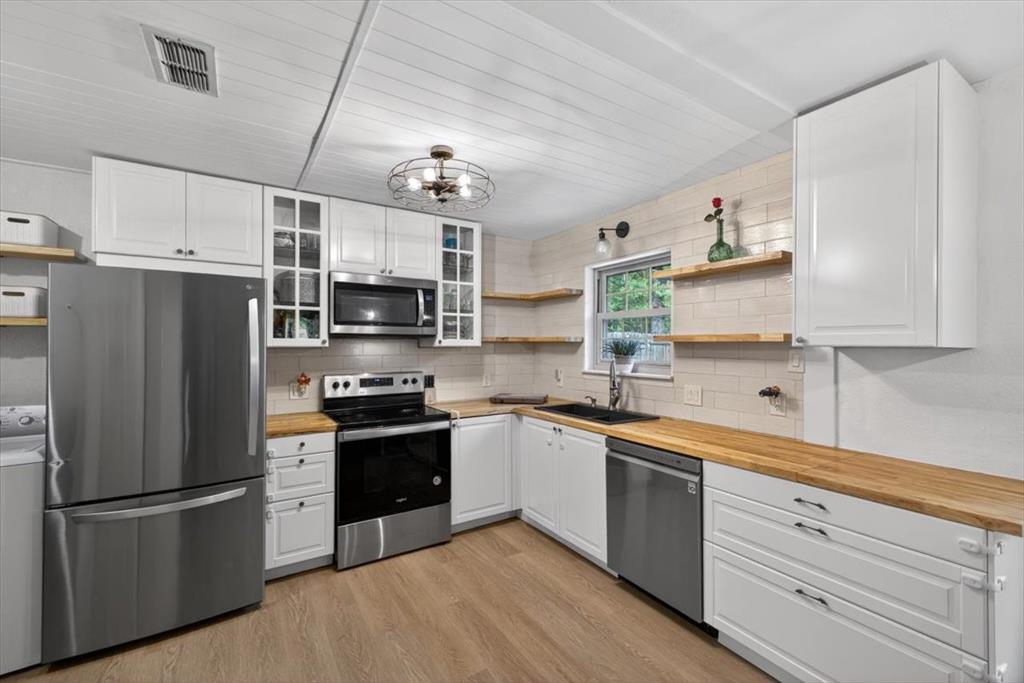 405 Pecan Street Azle, TX 76020 - Photo 13 of 33 Kitchen with open shelves, stainless steel appliances, and white cabinetry