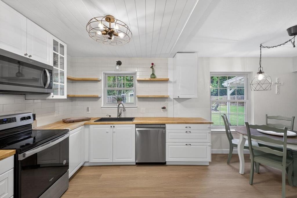 405 Pecan Street Azle, TX 76020 - Photo 15 of 33 Kitchen featuring stainless steel appliances, wooden counters, white cabinetry, light wood-style floors, and tasteful backsplash