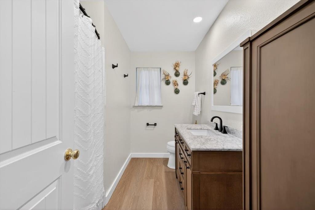 405 Pecan Street Azle, TX 76020 - Photo 19 of 33 Full bath featuring vanity, light wood finished floors, and a shower with shower curtain