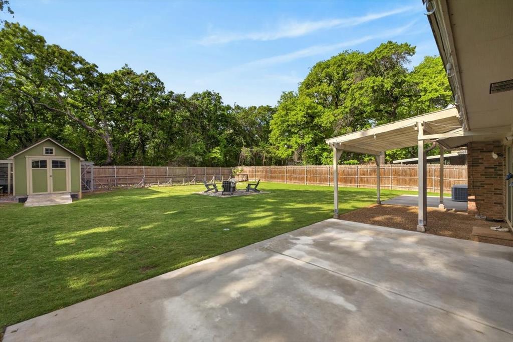 405 Pecan Street Azle, TX 76020 - Photo 27 of 33 Fenced backyard with a patio, an outdoor fire pit, and an outdoor structure