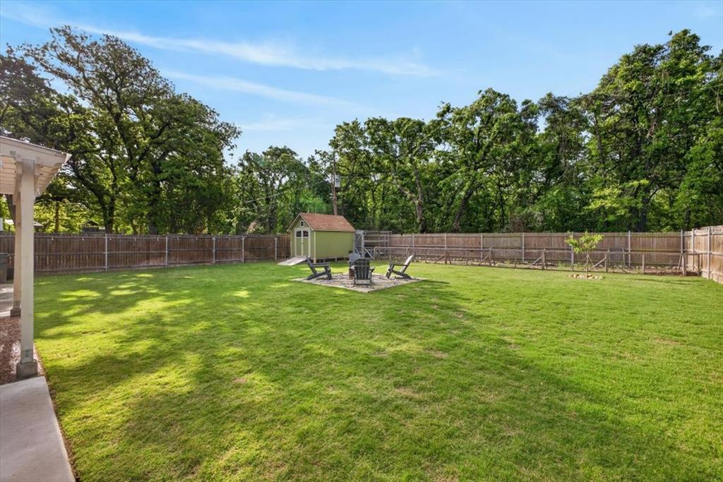 405 Pecan Street Azle, TX 76020 - Photo 29 of 33 Fenced backyard with a fire pit, a patio area, and a shed