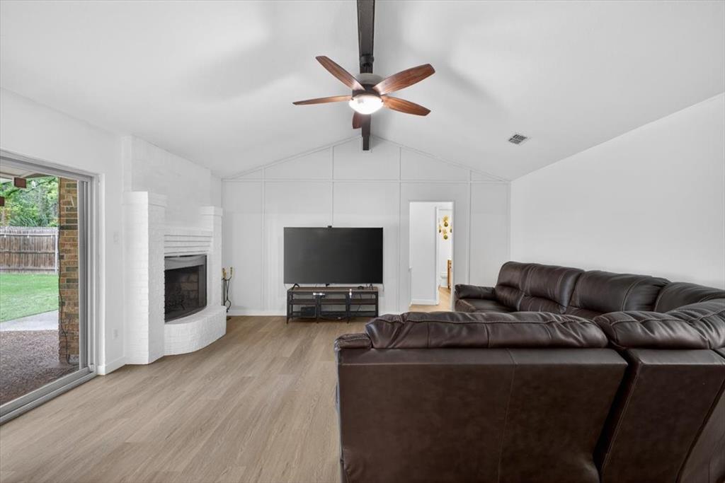 405 Pecan Street Azle, TX 76020 - Photo 7 of 33 Living area with beam ceiling, light wood finished floors, a ceiling fan, and a brick fireplace