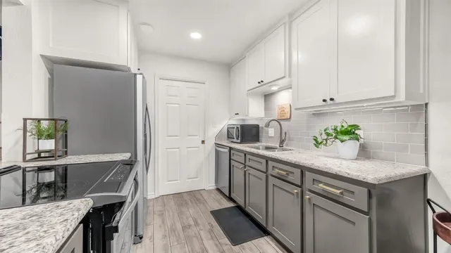 a kitchen with stainless steel appliances granite countertop a sink dishwasher and a refrigerator with wooden floor