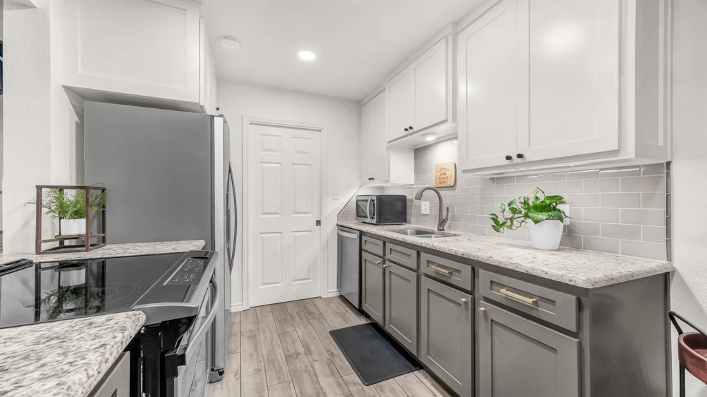 3059 Hells Gate Loop, Unit 7 Strawn, TX 76475 - Photo 16 of 36 a kitchen with stainless steel appliances granite countertop a sink dishwasher and a refrigerator with wooden floor
