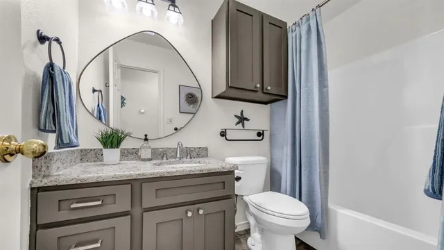 a bathroom with a granite countertop toilet sink and mirror