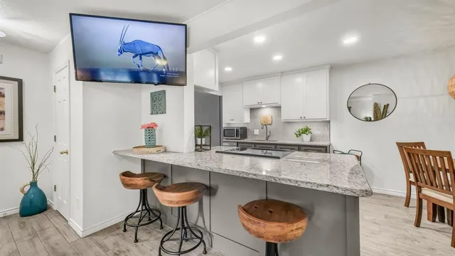 a kitchen with stainless steel appliances granite countertop a sink a stove a dining table and chairs