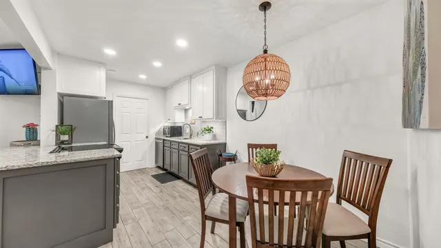 a dining room with wooden floor a chandelier a wooden table and chairs